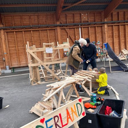 Kinder und Erwachsene basteln in einer grossen Halle mit Holz