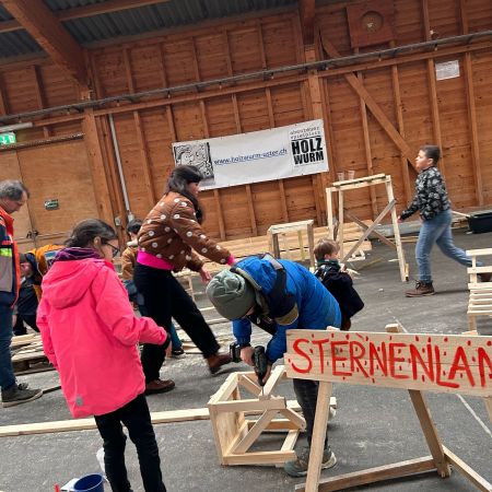 Kinder basteln in einer grossen Halle mit Holz